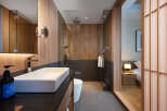 This modern hotel bathroom boasts a sleek, minimalist design with a walk-in shower and a spacious vanity.