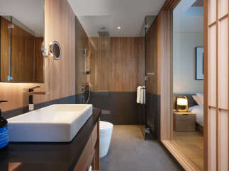 This modern hotel bathroom boasts a sleek, minimalist design with a walk-in shower and a spacious vanity.