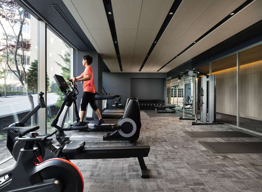 Modern gym with floor-to-ceiling windows offering natural light and city views.