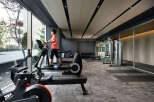 Modern gym with floor-to-ceiling windows offering natural light and city views.