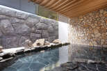 Indulge in tranquility at this luxurious onsen, featuring a serene outdoor bath nestled between stunning stone walls.