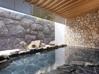 Indulge in tranquility at this luxurious onsen, featuring a serene outdoor bath nestled between stunning stone walls.