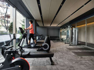 Modern gym with floor-to-ceiling windows offering natural light and city views.