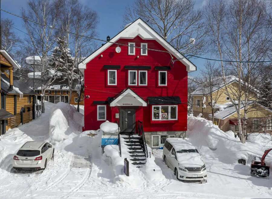 This charming red house is nestled in a snowy winter wonderland, offering a cozy and picturesque setting.
