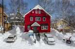 This charming red house is nestled in a snowy winter wonderland, offering a cozy and picturesque setting.