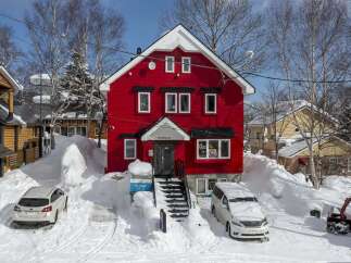 This charming red house is nestled in a snowy winter wonderland, offering a cozy and picturesque setting.