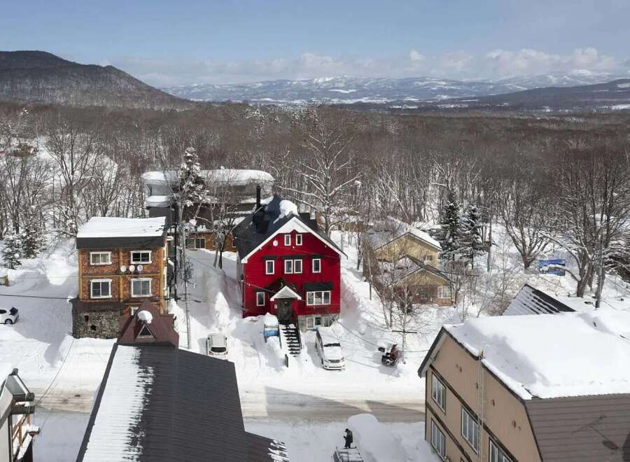 This charming red house is nestled in a snowy mountain town, offering breathtaking views.