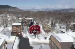 This charming red house is nestled in a snowy mountain town, offering breathtaking views.