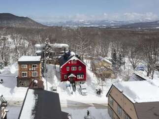 This charming red house is nestled in a snowy mountain town, offering breathtaking views.