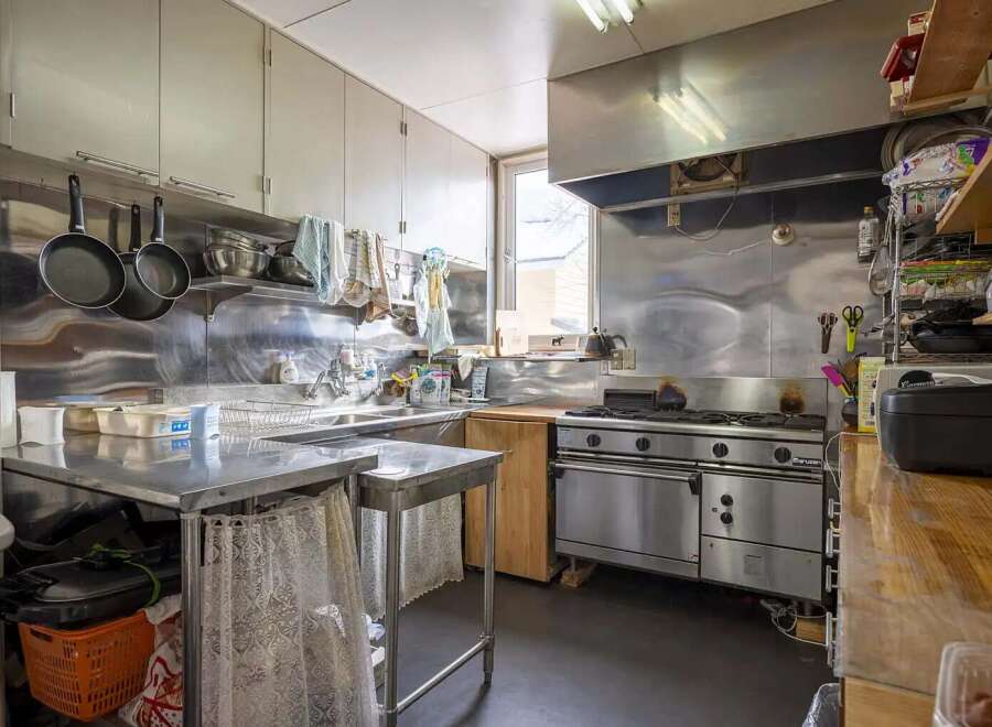 This commercial kitchen boasts stainless steel countertops and appliances, ample storage, and a large oven.