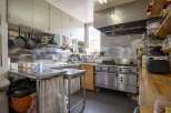 This commercial kitchen boasts stainless steel countertops and appliances, ample storage, and a large oven.