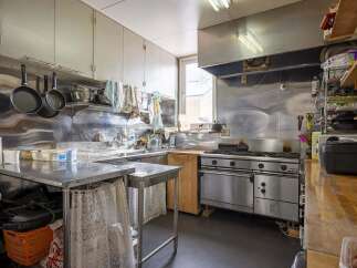 This commercial kitchen boasts stainless steel countertops and appliances, ample storage, and a large oven.