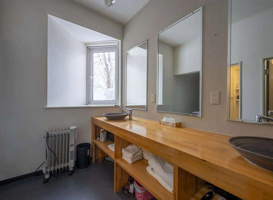 This cozy bathroom boasts a light wood vanity with built-in shelving, perfect for storing towels and toiletries.