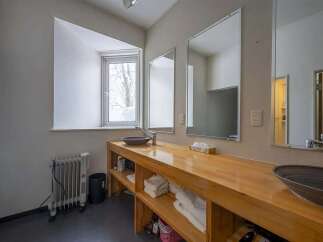 This cozy bathroom boasts a light wood vanity with built-in shelving, perfect for storing towels and toiletries.