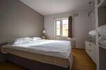 Cozy bedroom with a comfortable double bed, crisp white linens, and plenty of natural light from a large window.