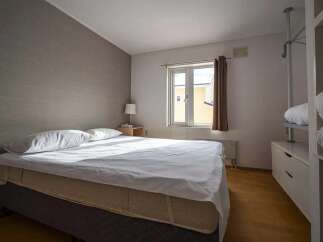 Cozy bedroom with a comfortable double bed, crisp white linens, and plenty of natural light from a large window.