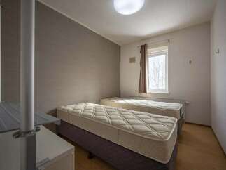 Cozy twin bedroom with neutral wall tones and natural light from a window.