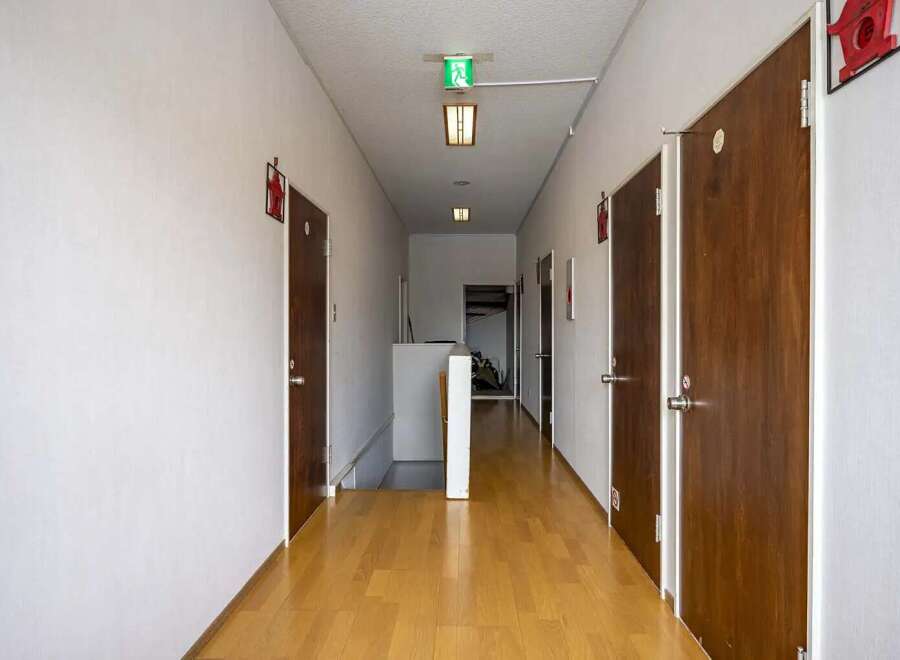 This hallway features light wood flooring, neutral-colored walls, and multiple doors leading to various rooms.
