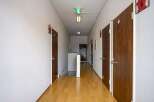 This hallway features light wood flooring, neutral-colored walls, and multiple doors leading to various rooms.
