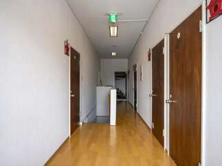 This hallway features light wood flooring, neutral-colored walls, and multiple doors leading to various rooms.