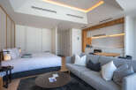 Modern studio apartment featuring a comfortable queen-size bed, a stylish grey sofa, and a fully equipped kitchenette.