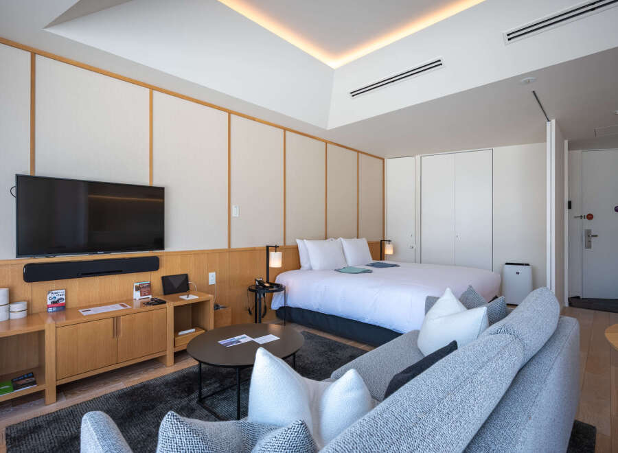This modern hotel room boasts a comfortable king-size bed, a sleek flat-screen TV, and a cozy seating area perfect for relaxing.