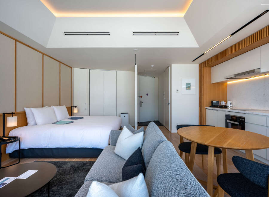 This modern studio apartment boasts a comfortable queen-size bed, a well-equipped kitchenette, and a stylish living area with a cozy sofa.