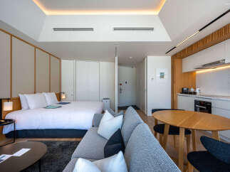 This modern studio apartment boasts a comfortable queen-size bed, a well-equipped kitchenette, and a stylish living area with a cozy sofa.