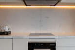 Modern kitchen with sleek white cabinets and marble countertops.