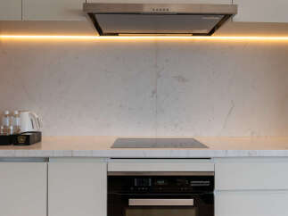 Modern kitchen with sleek white cabinets and marble countertops.