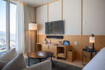 Relax in style in this modern hotel room, featuring floor-to-ceiling windows with mountain views, a comfortable seating area, and a sleek entertainment center.