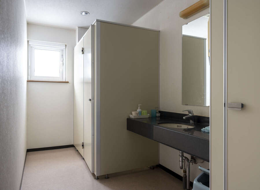 This clean and simple restroom features a single sink vanity with a dark countertop and a light beige wall.