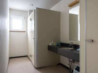 This clean and simple restroom features a single sink vanity with a dark countertop and a light beige wall.