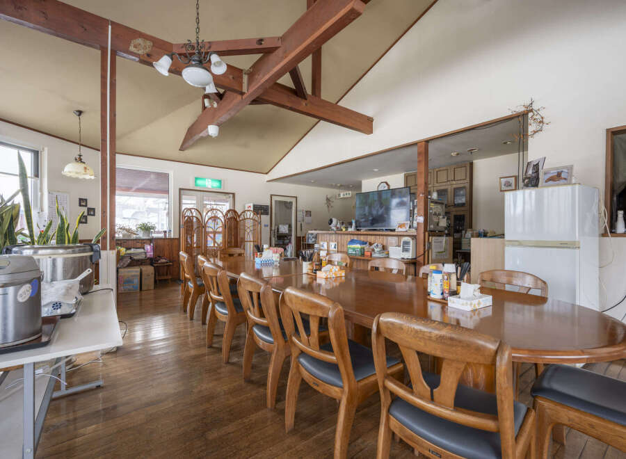 This cozy lodge boasts a large communal dining table perfect for group gatherings, featuring a rustic wooden design and comfortable seating.