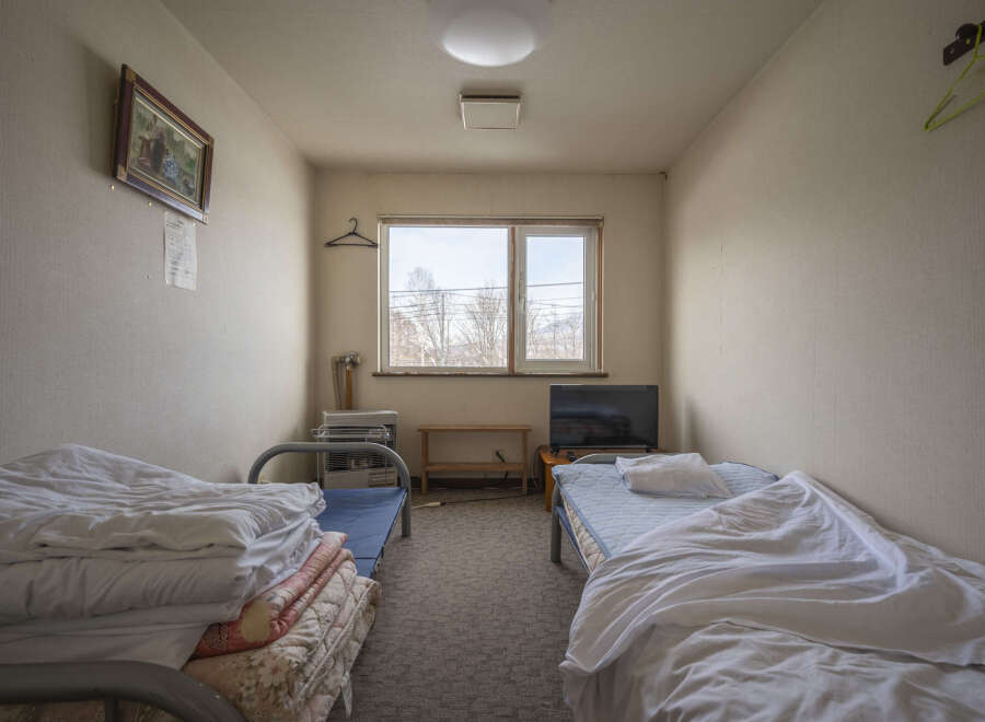 Cozy twin room with two single beds, a small TV, and a heater.