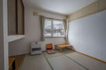 Cozy Japanese-style room with tatami mats, a low table, and a heater.