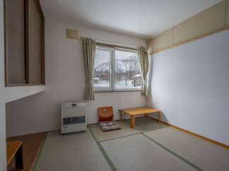 Cozy Japanese-style room with tatami mats, a low table, and a heater.