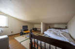 Cozy attic bedroom with tatami mats, a wooden bed frame, and a small TV.