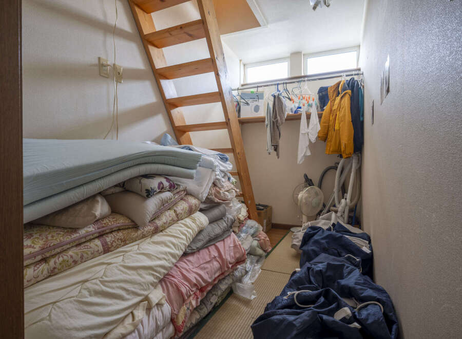 Cozy attic room with wooden ladder access, offering ample storage space.