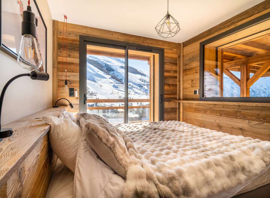 Wake up to breathtaking mountain views from this cozy chalet bedroom.
