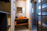 Modern bathroom with stylish orange sink and wooden shelving.