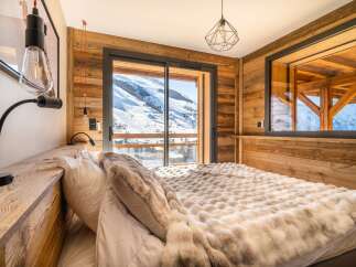 Wake up to breathtaking mountain views from this cozy chalet bedroom.