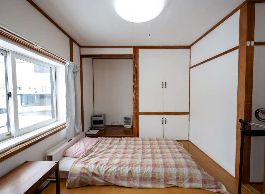 Cozy Japanese-style room with a futon bed, built-in closet, and large window.