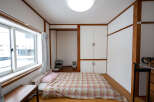 Cozy Japanese-style room with a futon bed, built-in closet, and large window.