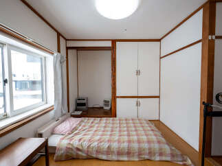 Cozy Japanese-style room with a futon bed, built-in closet, and large window.