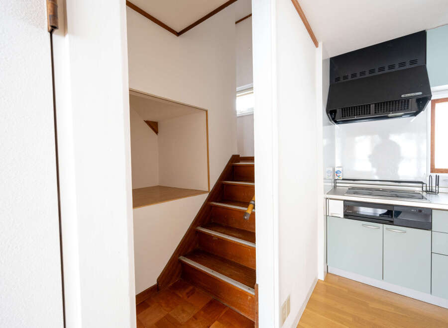 Cozy house with wooden stairs leading to an upper level, featuring a built-in storage space under the stairs.