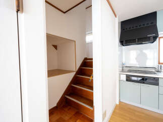 Cozy house with wooden stairs leading to an upper level, featuring a built-in storage space under the stairs.