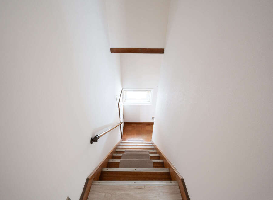 Modern minimalist staircase with wooden steps and metal handrail.