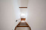 Modern minimalist staircase with wooden steps and metal handrail.