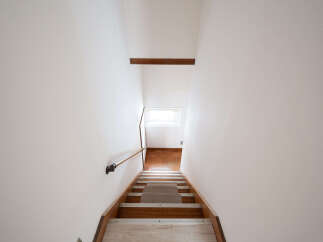 Modern minimalist staircase with wooden steps and metal handrail.